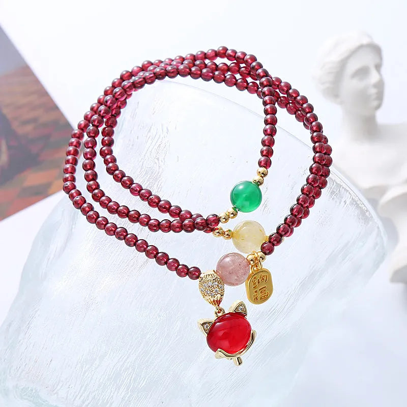 Purplish red garnet bead bracelet with a silver fox charm and adjustable rope fastening.