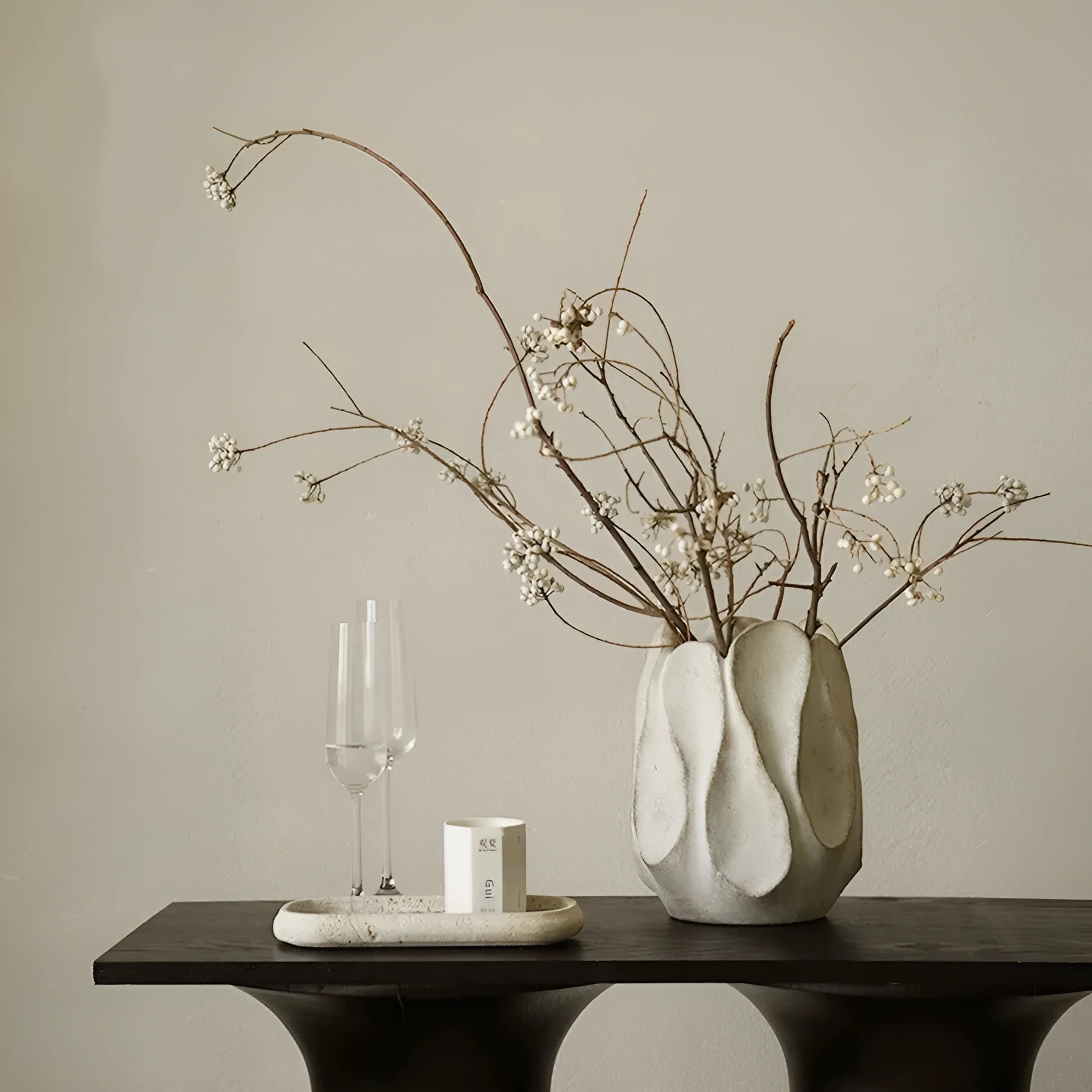 Irregularly shaped art ceramic vase in a low style profile on a wooden surface