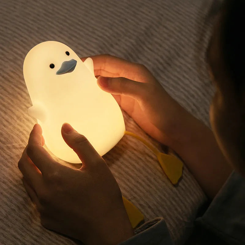Seagull silicone night light in yellow colour with soft warm glow on bedside table