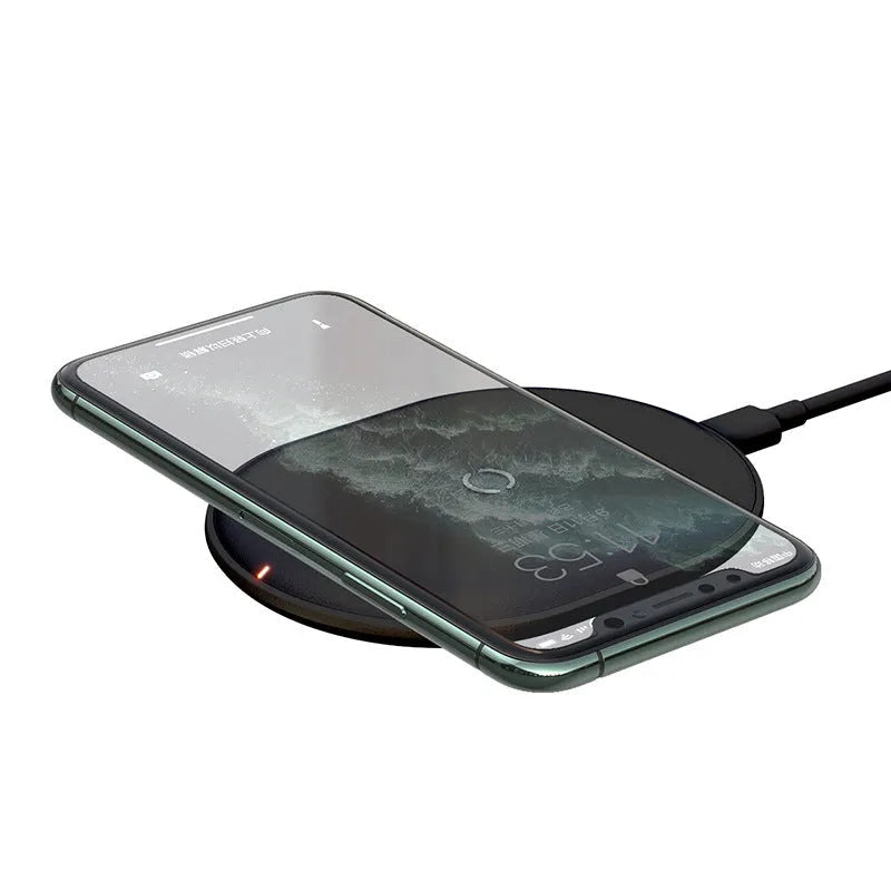 Black Baseus wireless charging pad with a textured surface and a small LED light, next to a mobile phone.