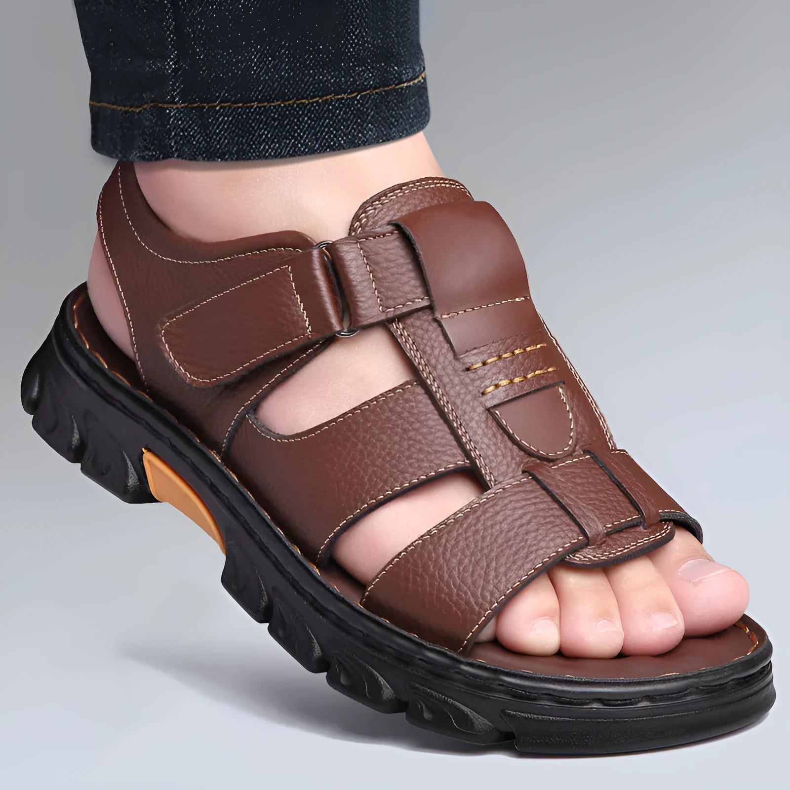 Men's brown cowhide leather sandals with velcro strap and open toe on a beach background