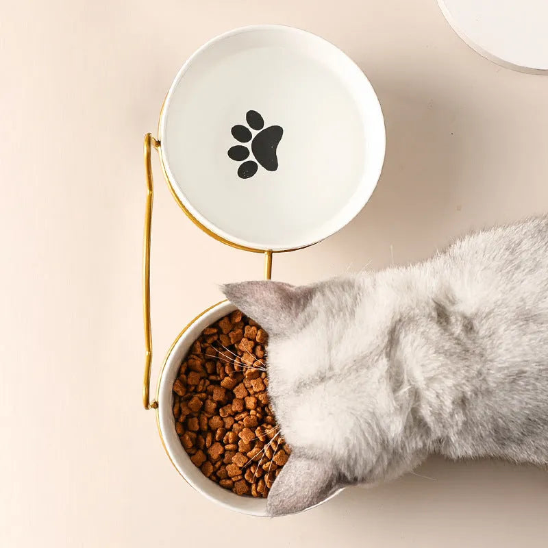 White ceramic cat bowl with paw print design in a black iron cat-ear frame.