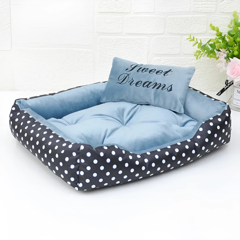 Polka dot print square dog bed with a matching embroidered pillow in grey, shown in a home setting.