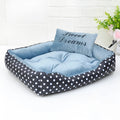 Polka dot print square dog bed with a matching embroidered pillow in grey, shown in a home setting.