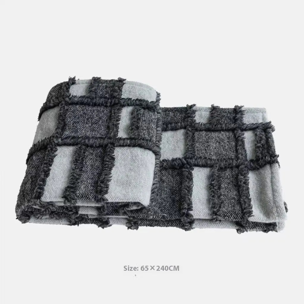 Modern minimalist bedding set with grey and white plaid blanket, pillowcase, and round pillow on bed