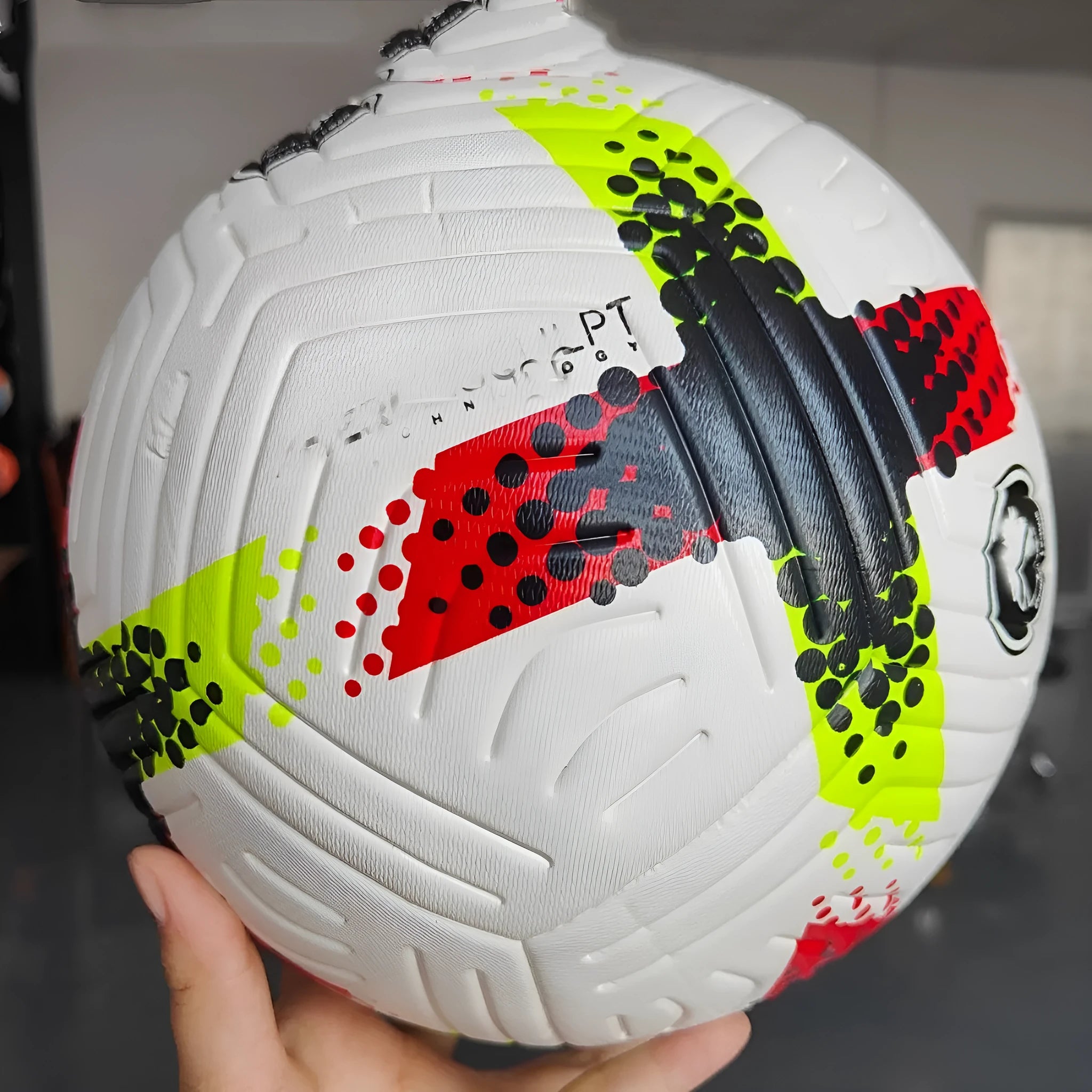 Fluorescent green size 5 PU football with seamless thermal adhesive construction on a pitch.