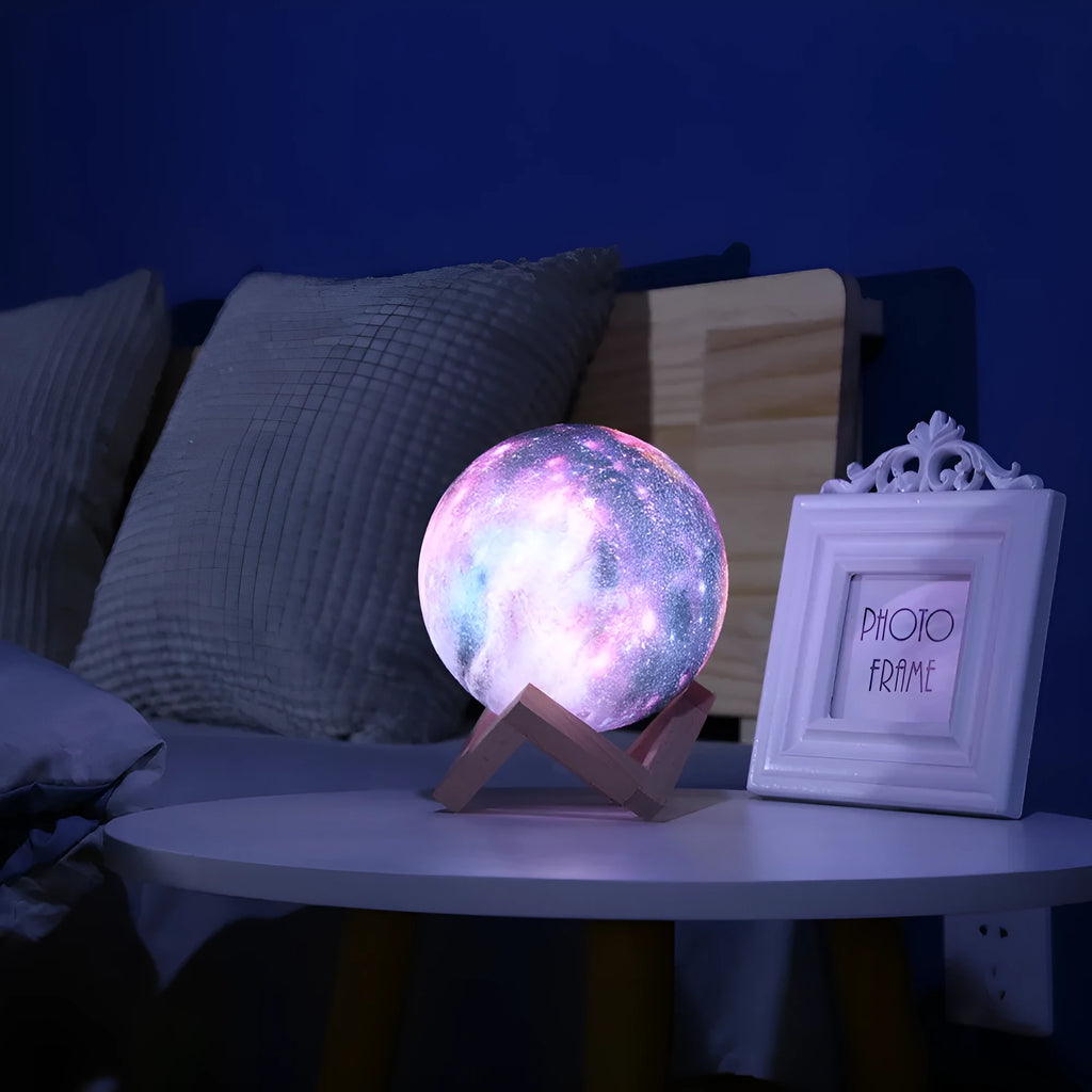 3D-printed spherical moon night light with colour-changing LED glow on a dark surface.