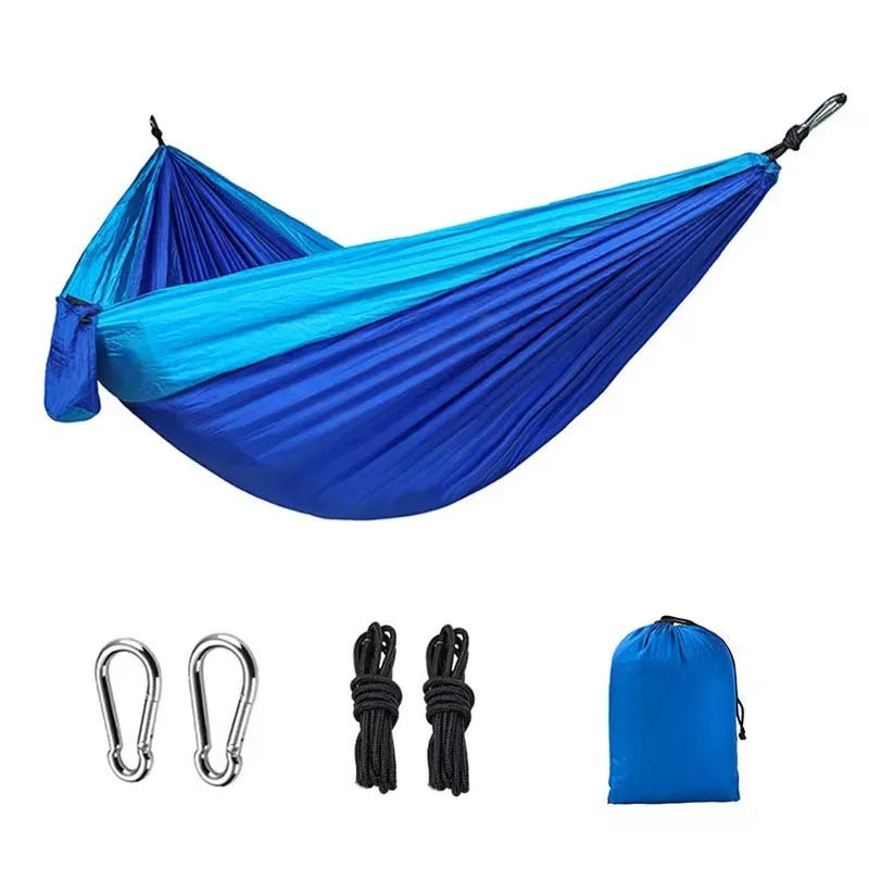 Blue nylon camping hammock hanging between trees with parachute fabric construction