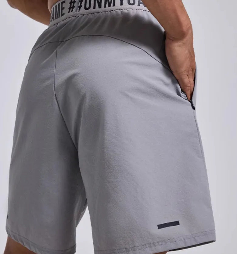 Man wearing loose black sports shorts with letter print detail, showing elastic waist and cropped length.