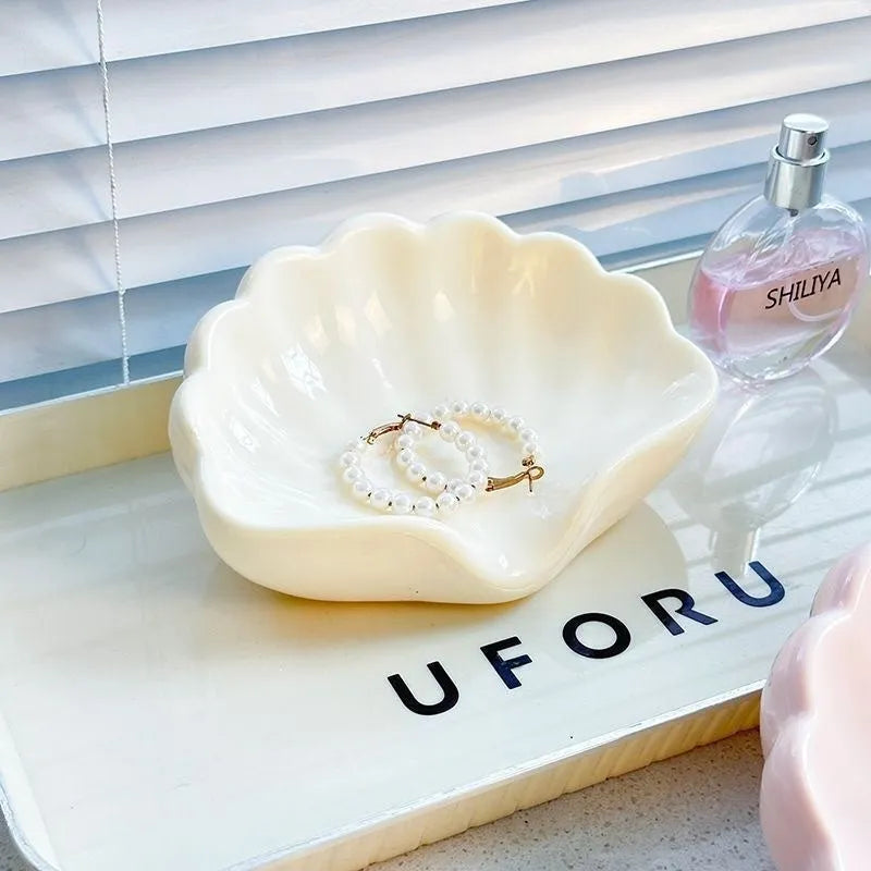 White shell-shaped plastic soap dish for bathroom use on a countertop.