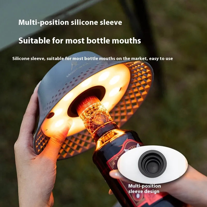 Beige and grey wine bottle shaped camping lantern with USB-C port on a wooden table.