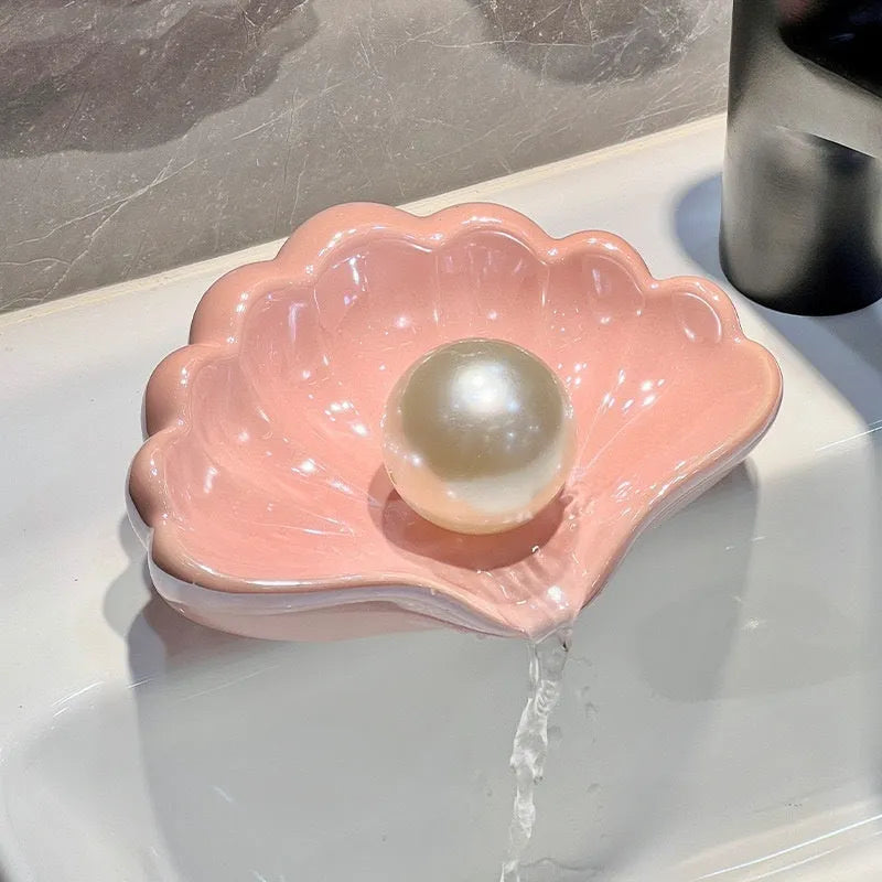 White shell-shaped plastic soap dish for bathroom use on a countertop.