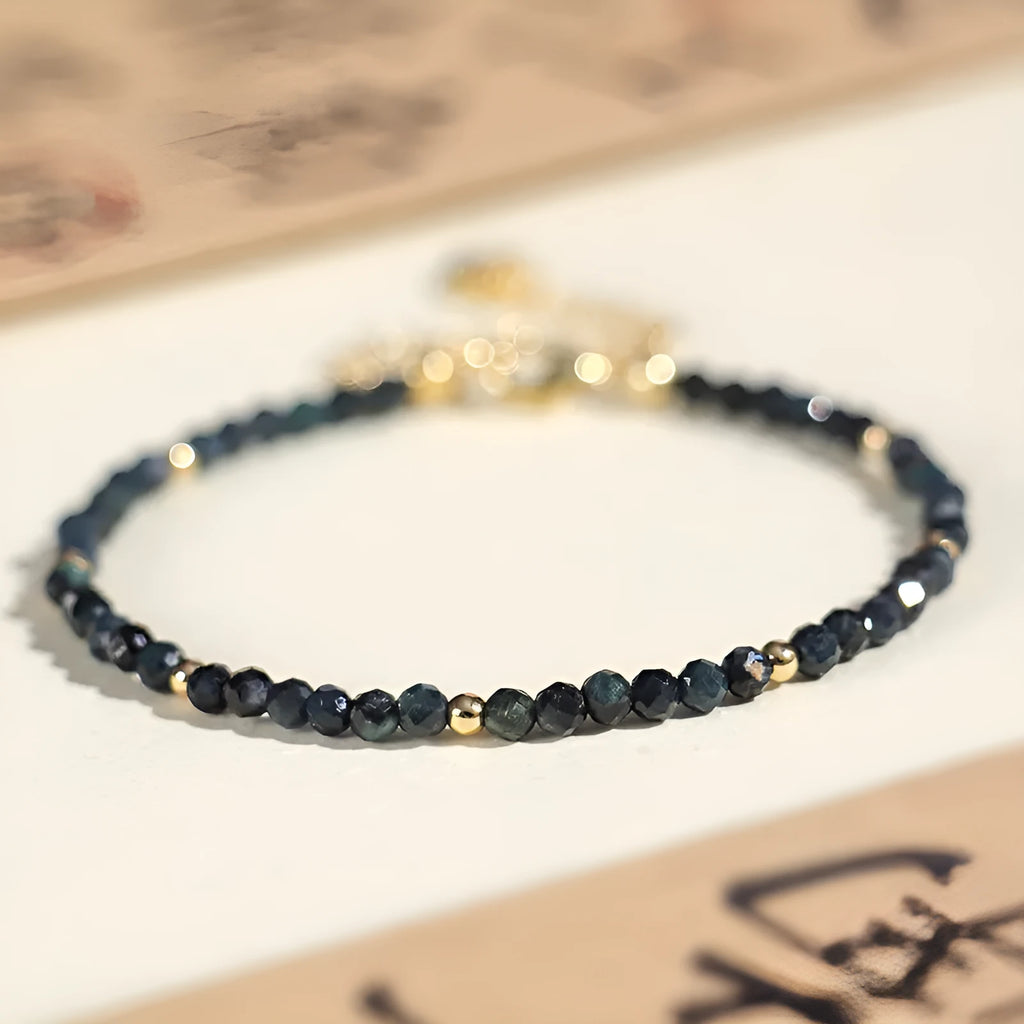 Close-up of a 3mm blue tourmaline cut bead spacer bracelet on a wrist.