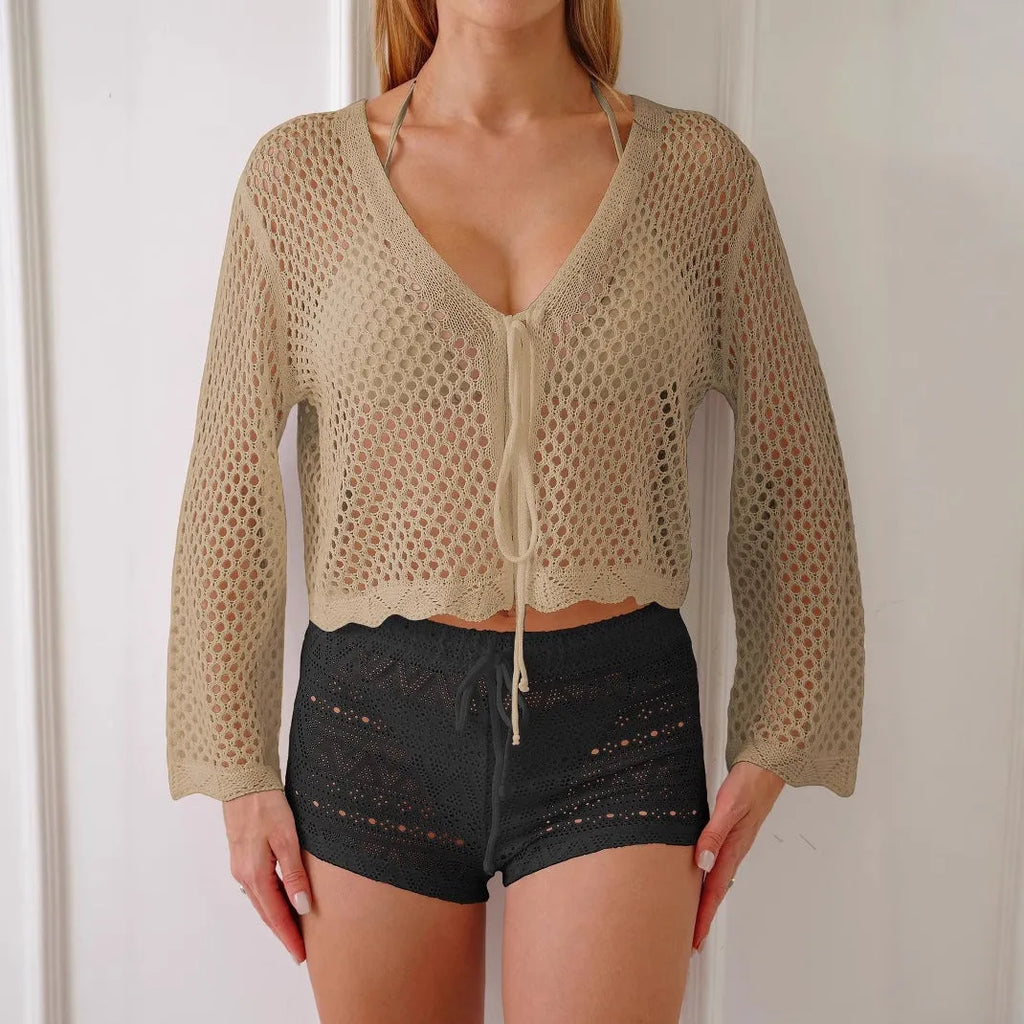 Short apricot coloured women's cardigan blouse with long bell sleeves on a hanger.