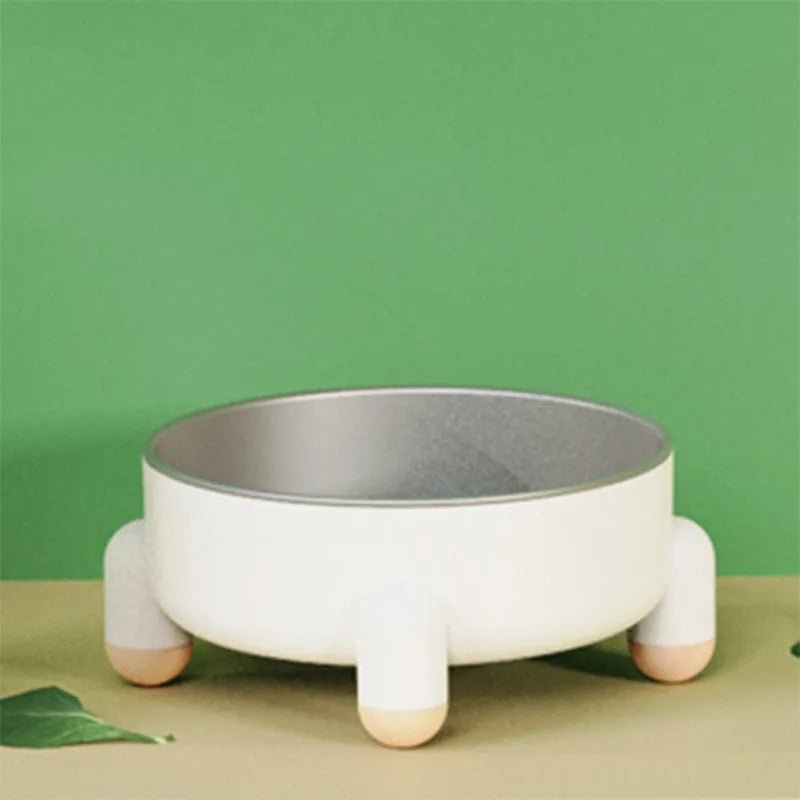 Green stainless steel pet bowl with a non-slip rubber ring and raised foot design on a wooden floor.