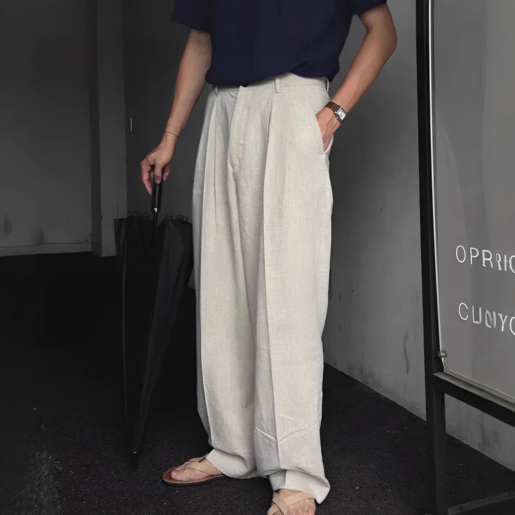 Man wearing apricot-coloured wide-leg cotton linen suit trousers with a pencil leg opening.