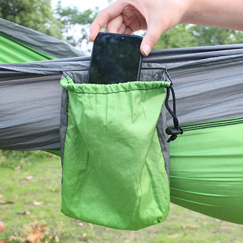 Blue nylon camping hammock hanging between trees with parachute fabric construction