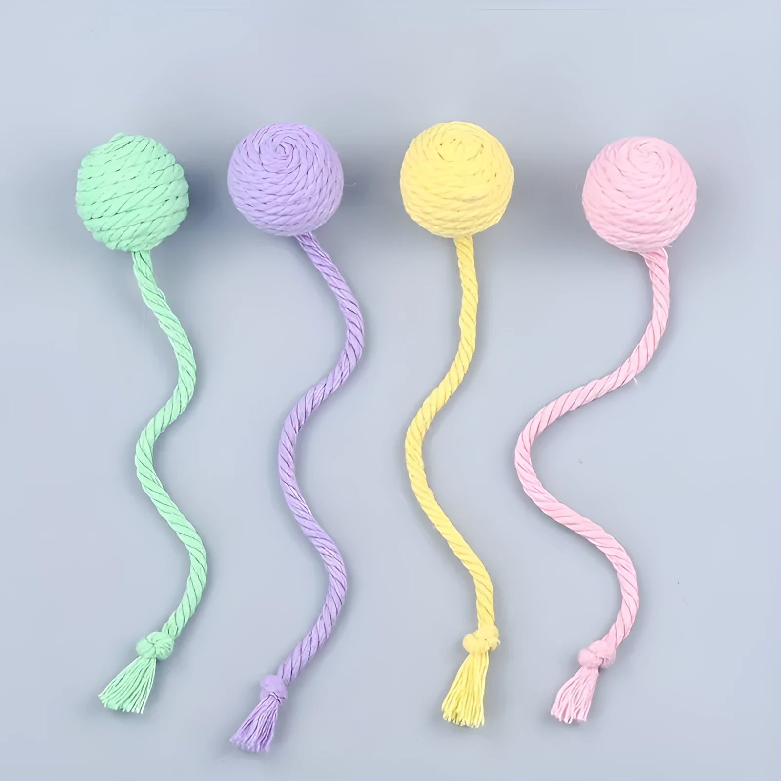 Green cat toy ball with attached rope and internal bell next to a pink one.