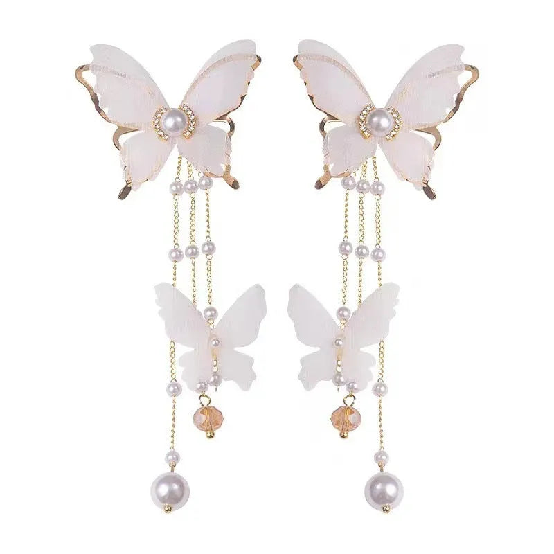 A pair of white butterfly-design earrings with pearl and rhinestone details on a tassel lace style.