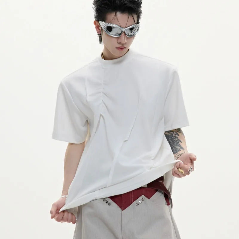Man wearing a loose grey cotton T-shirt with three-dimensional pleated detailing on the front.