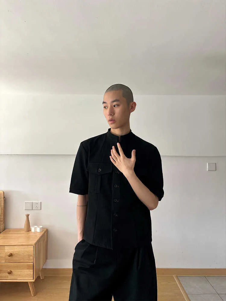 Handmade black half-sleeve hunting shirt with shirt collar on a hanger.