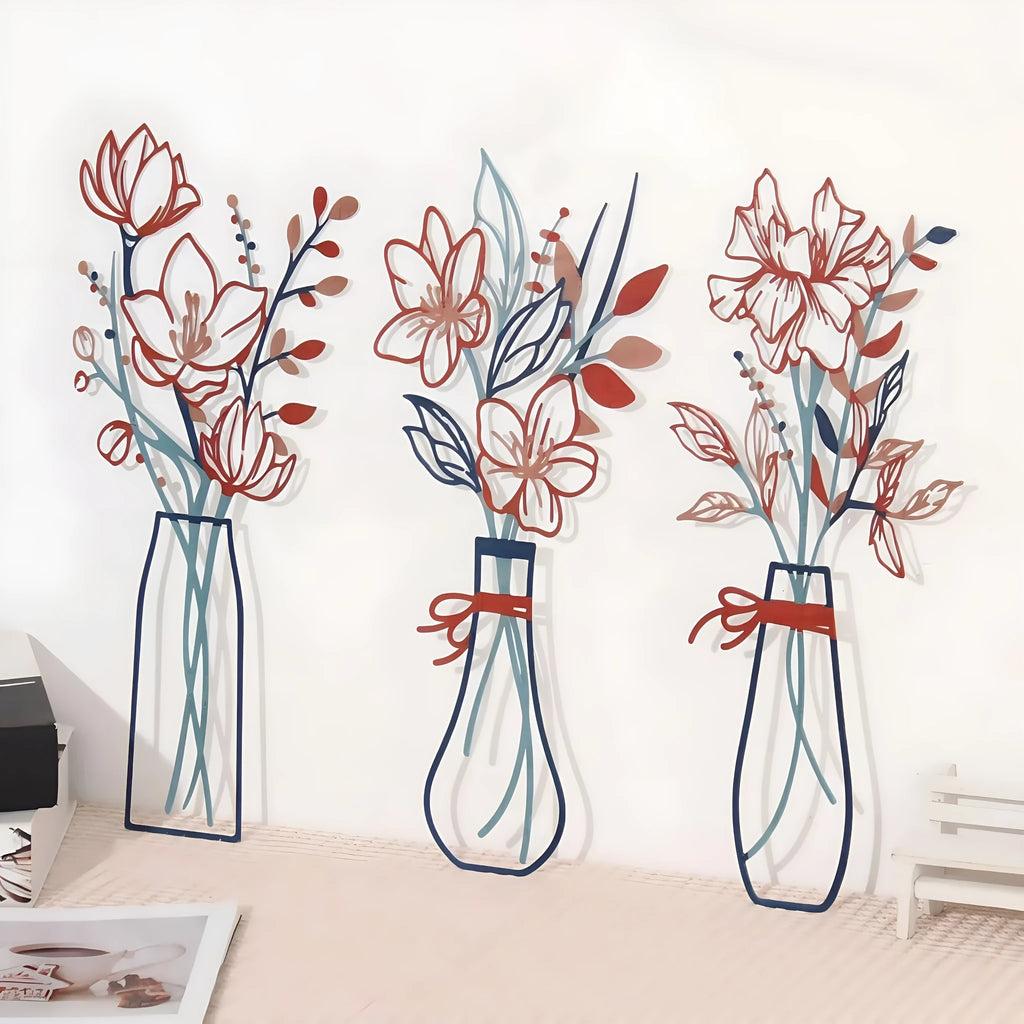 Set of three metal flower wall art pieces with colour vase accents on a white wall.