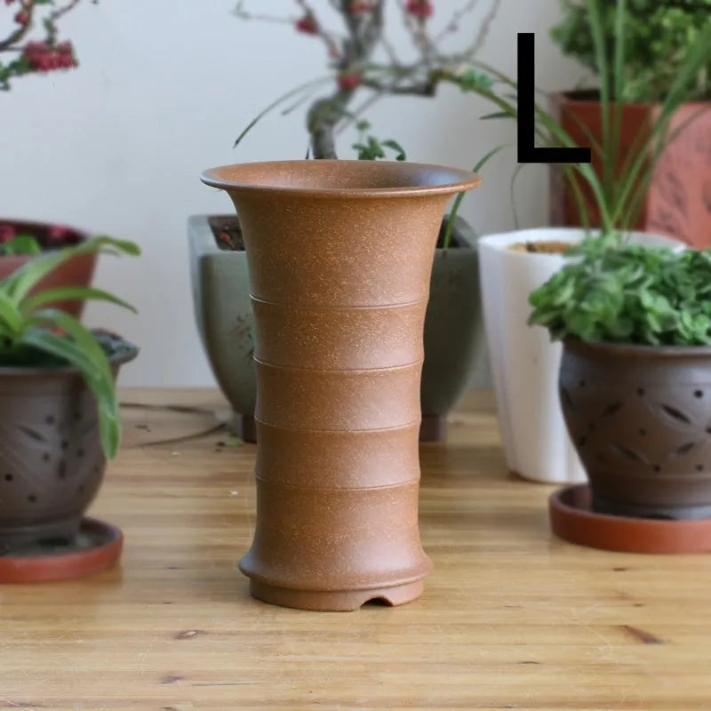 Boutique handmade descending slope ceramic orchid pot in mud purple sand on desktop