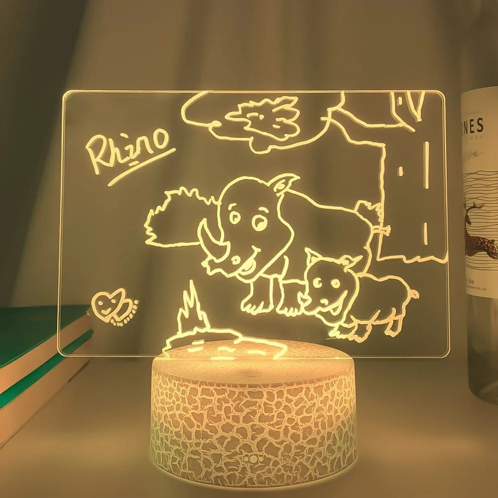 3D acrylic LED message board night light with remote control and marker pen on a desk.