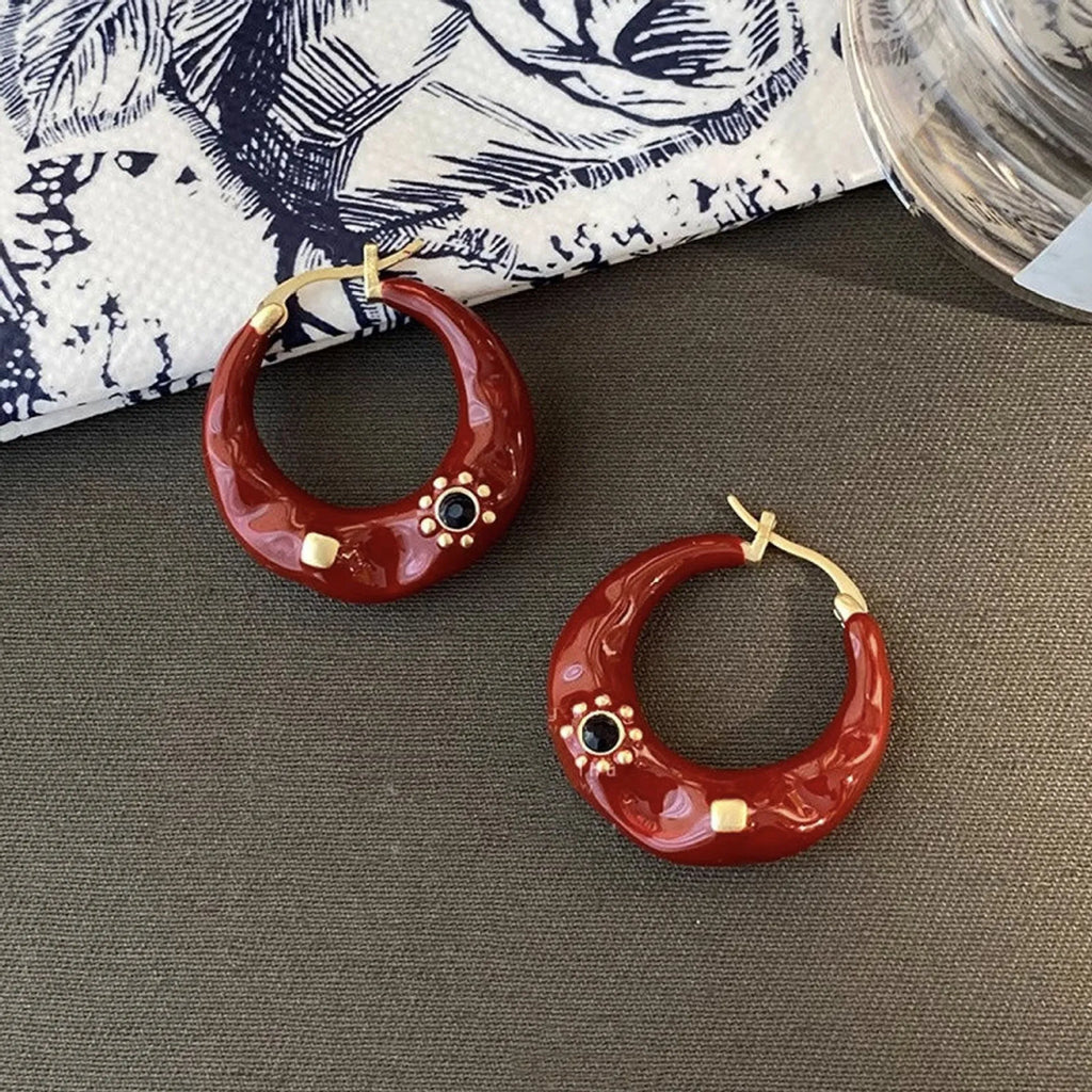 A pair of retro alloy ear studs with a dripping oil finish and black rhinestone detail.