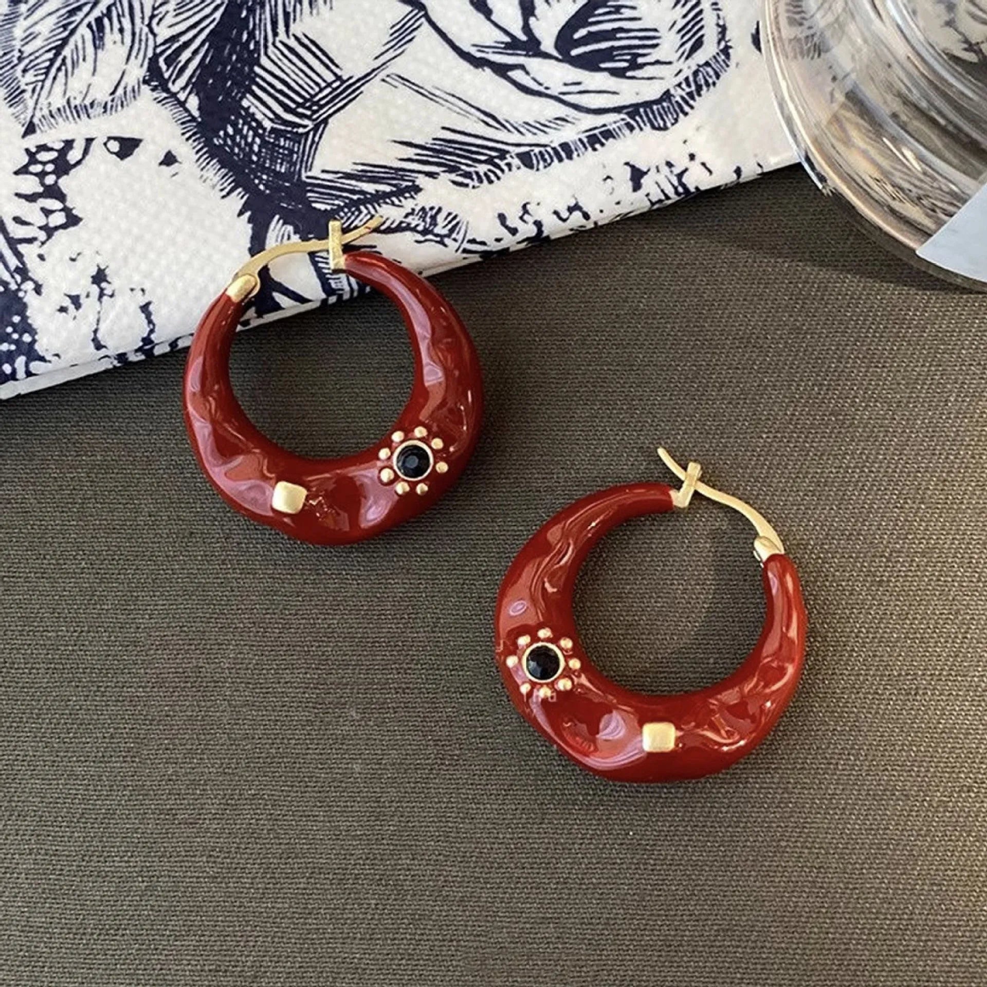 A pair of retro alloy ear studs with a dripping oil finish and black rhinestone detail.