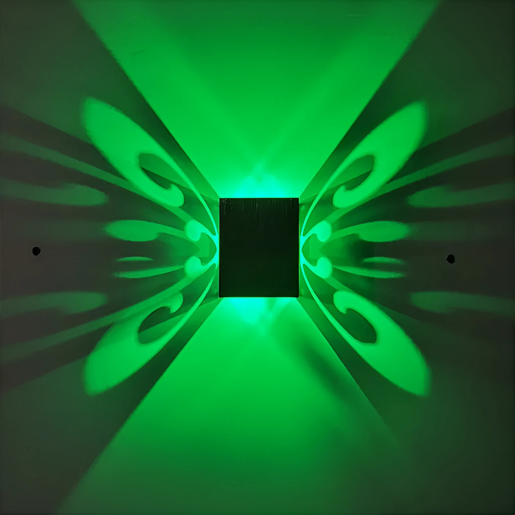 Modern aluminium butterfly-shaped LED wall lamp on a white wall with remote control.