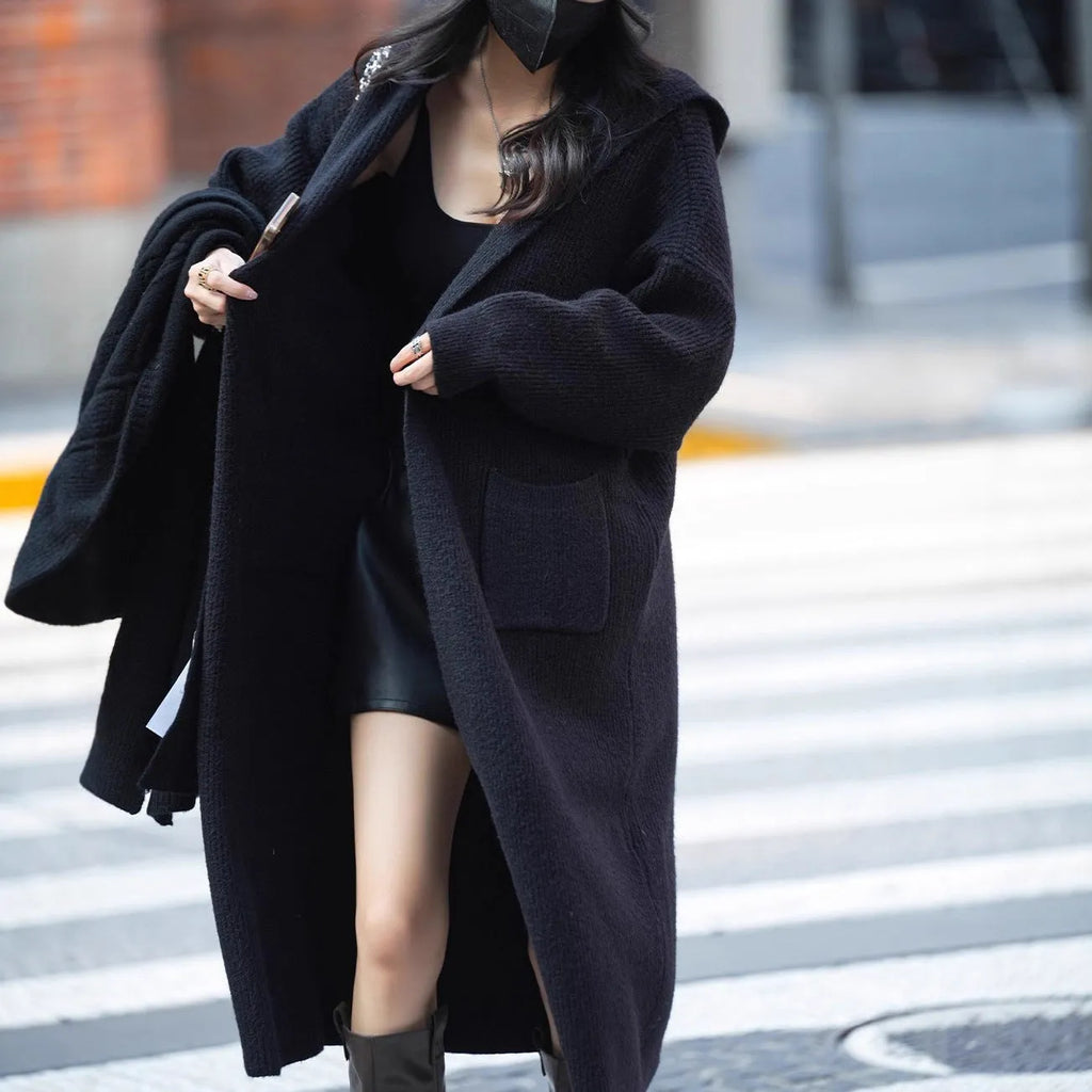 Long grey knitted hooded trench coat worn open as a cardigan.