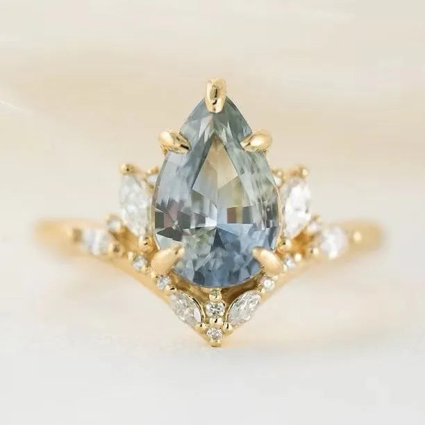Gold alloy ring with blue crystal diamond inlay and floral design on white background