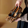 Women's black square toe stiletto ankle-strap heels with horse hair upper on a plain background.