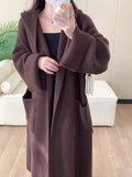 Loose grey hooded cardigan coat with raglan sleeves shown on a hanger.