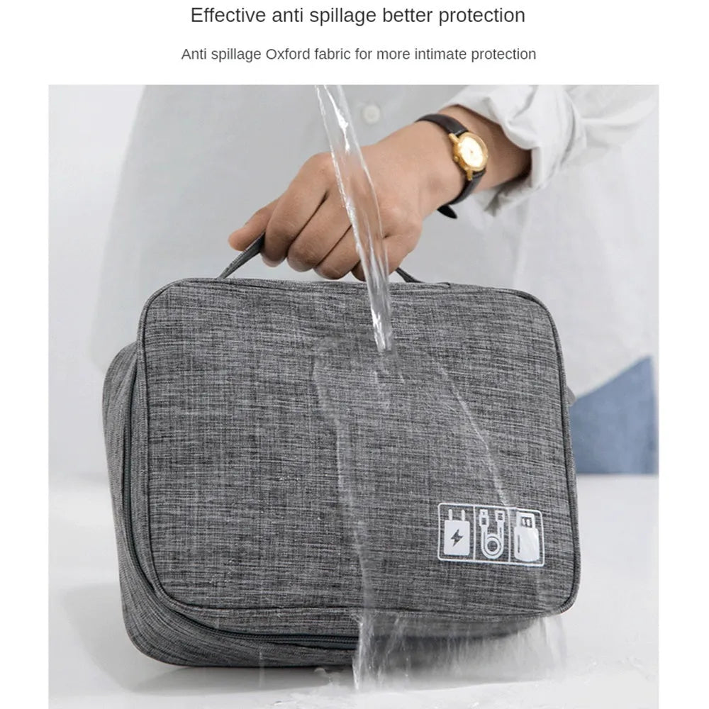Black waterproof electronics travel organizer case open, showing mesh pockets, elastic loops and removable padded dividers.