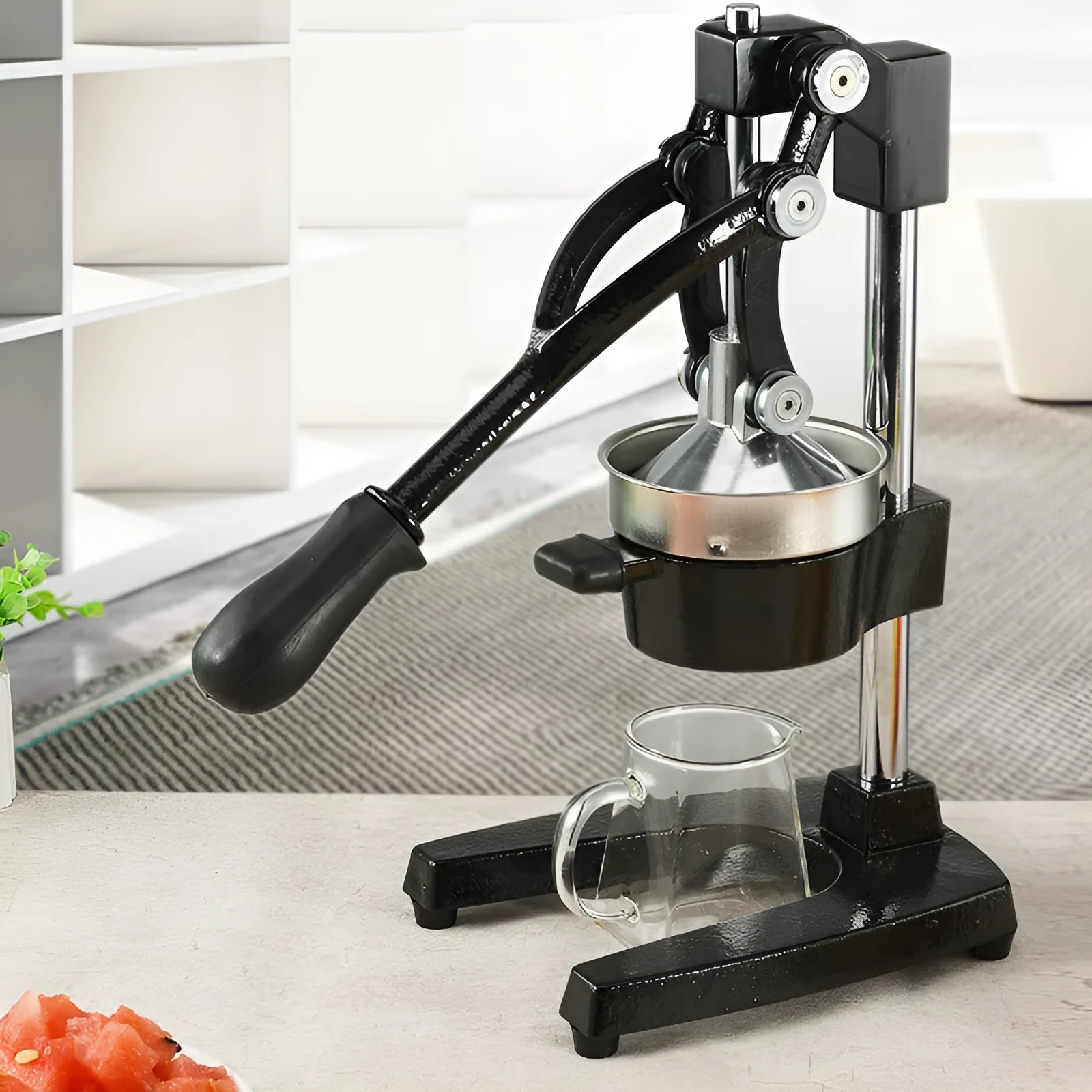 Black cast iron manual citrus juicer with stainless steel cone and lever, 40cm tall on a table.