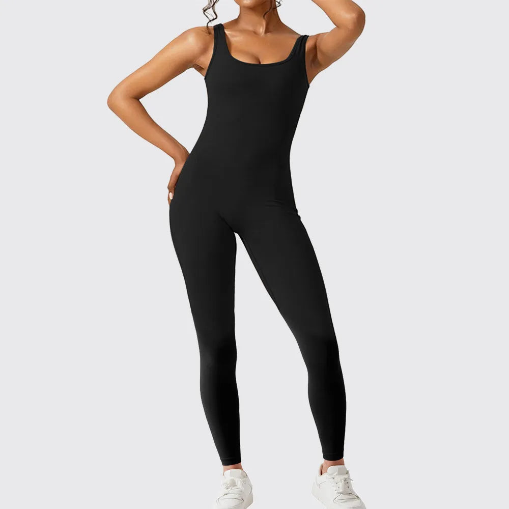 Woman wearing a sleeveless army green flare jumpsuit for yoga.