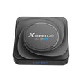 Android 11.0 set-top TV box with remote control and cables on a wooden table.