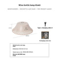 Beige and grey wine bottle shaped camping lantern with USB-C port on a wooden table.