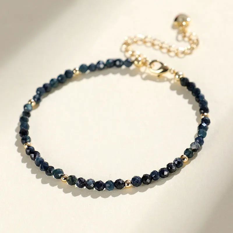 Close-up of a 3mm blue tourmaline cut bead spacer bracelet on a wrist.