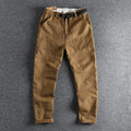 Man wearing mid-waist khaki cotton work trousers with a zipper fly and straight leg cut.