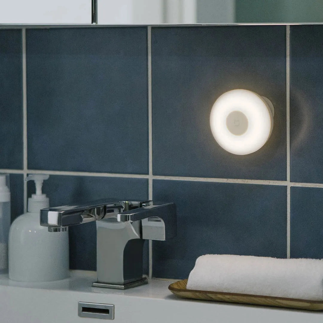 White cube-shaped Mijia bedside night light with motion sensor and Bluetooth on a wooden table.