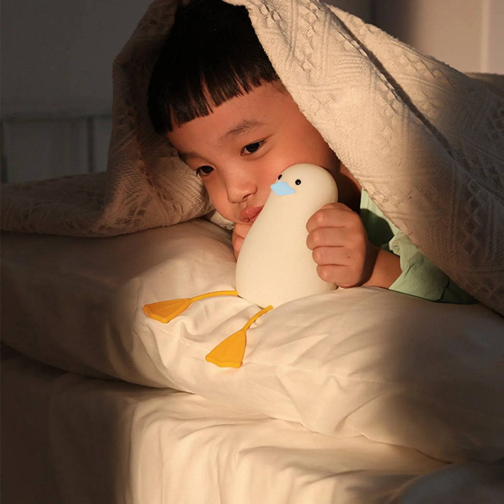 Seagull silicone night light in yellow colour with soft warm glow on bedside table