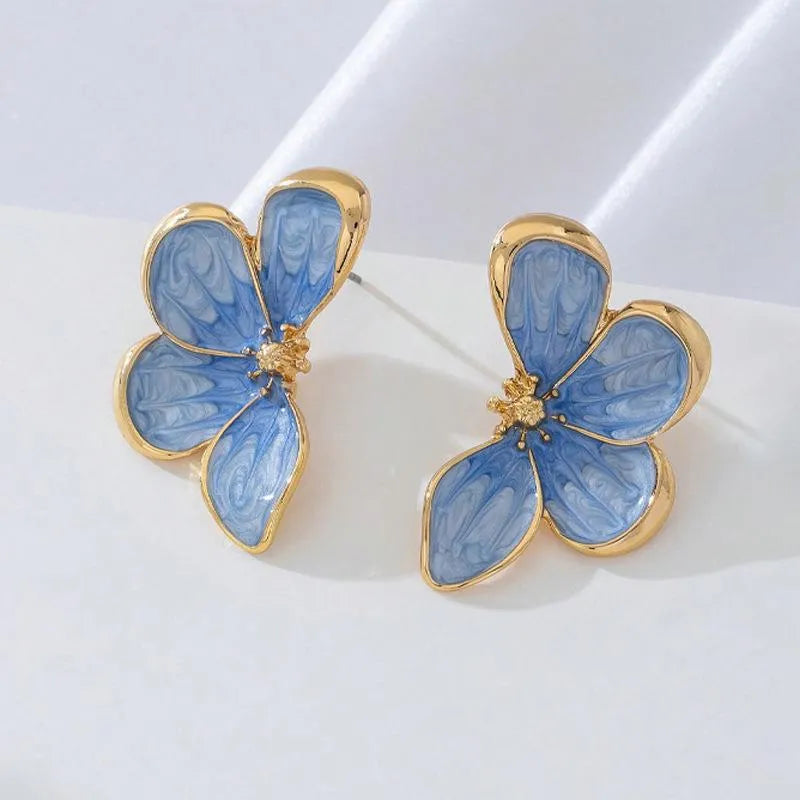 Three-dimensional flower earrings in blue and red colour options on a neutral background