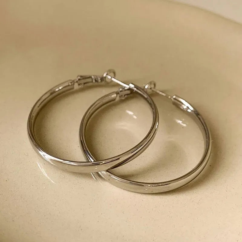 A pair of large 40mm gold metal circle hoop earrings on a white background.