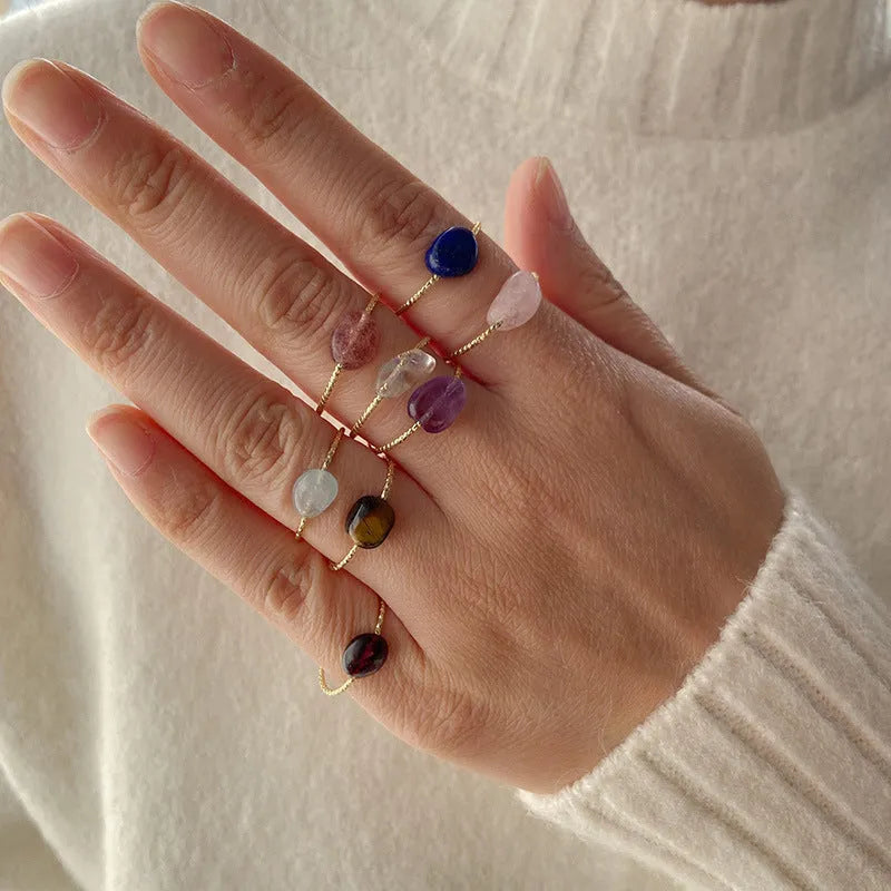 Geometric silver-toned ring setting with a central oval of blue and white banded agate stone on a woman's hand.