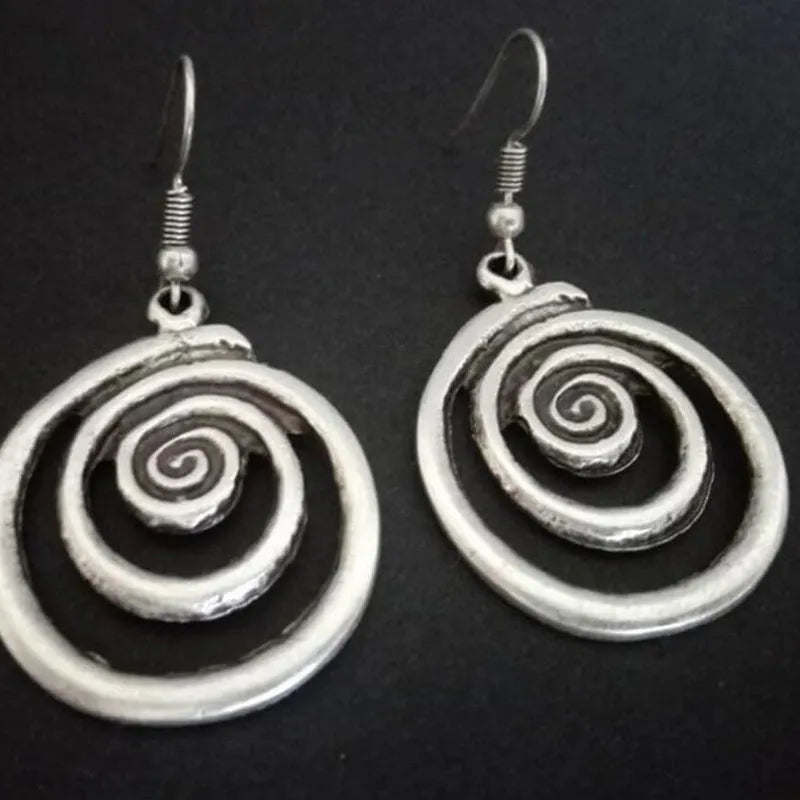 Close-up of silver-coloured geometric spiral earrings with a distressed retro finish.
