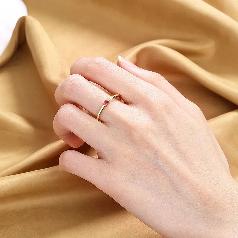 A women's fine copper circle ring with a single diamond, shown in blue, green, red, and white colour options.