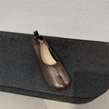 Women's brown split toe horseshoe design chunky heel pumps on a white background.